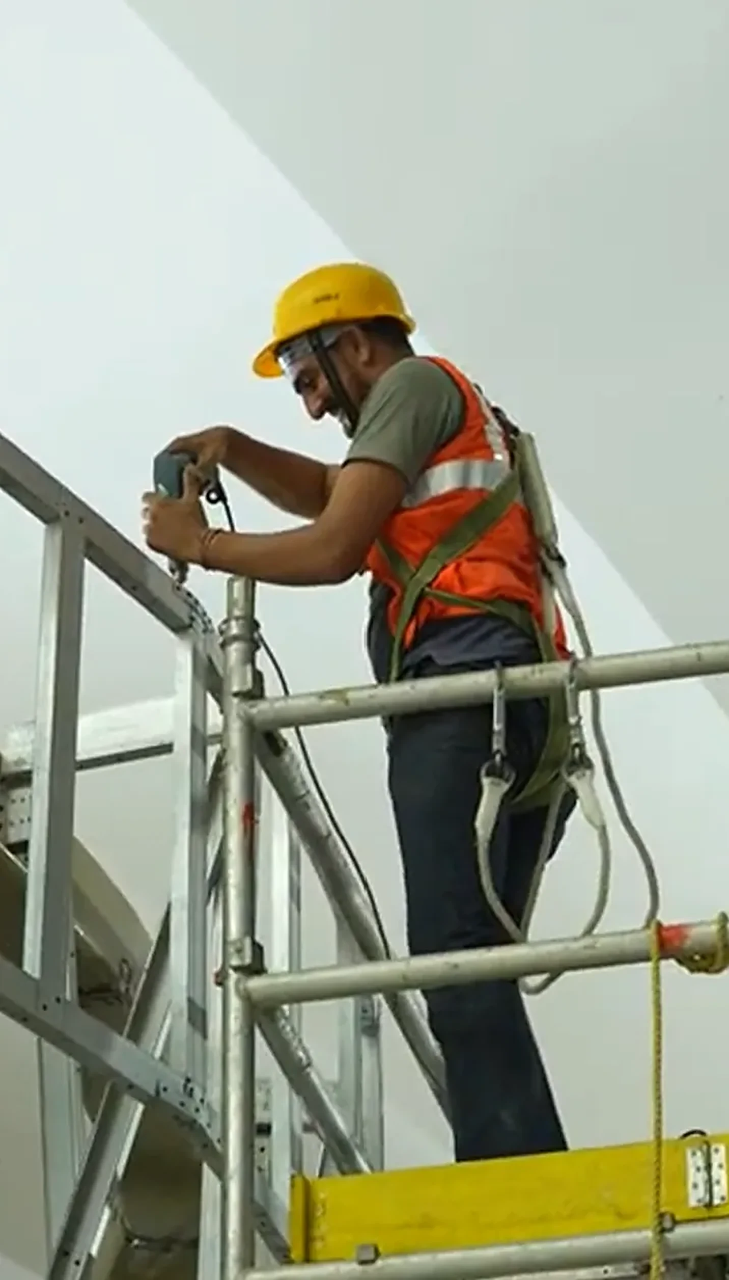 Installer in a yellow helmet assembling a railing on site